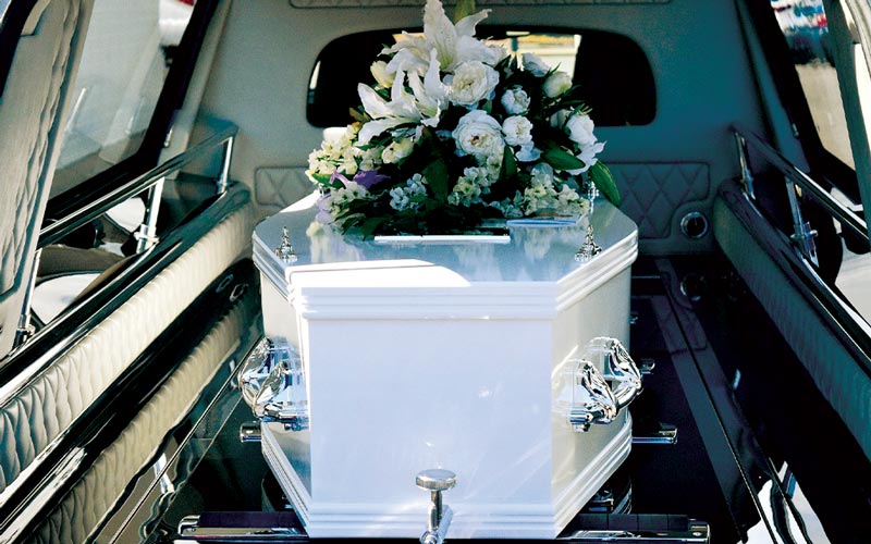 Cofano funebre Milano: bara bianca con fiori dentro la macchina