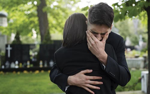 Le 5 fasi del lutto: persona che abbraccia e piange al funerale