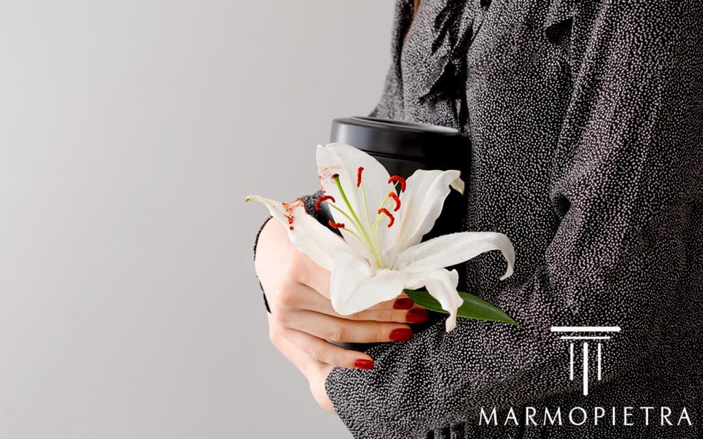 Monumentini Cimiteriali Cinerari Milano: ragazza con urna di ceneri e fiore in mano